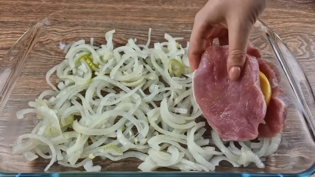 Pečené vepřové maso proložené bramborami na cibulce