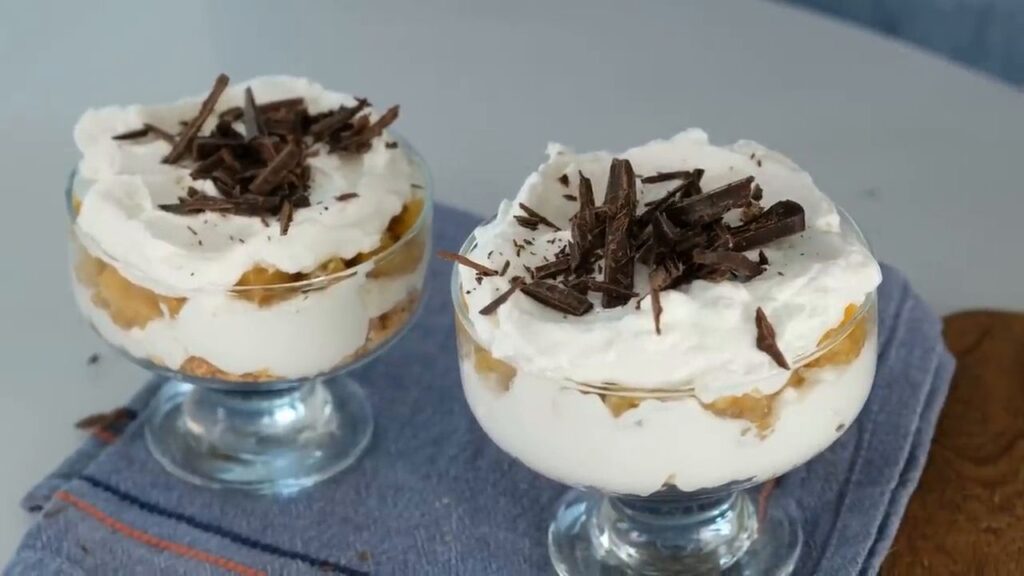 Karamelizované banány se smetanovým krémem podávané ve sklenicích, zdobené čokoládou