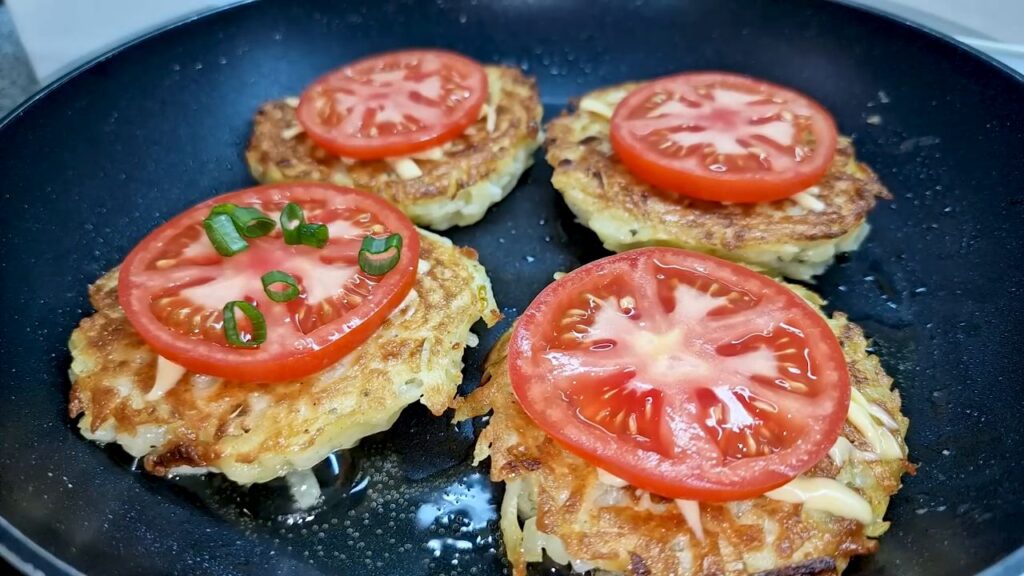 Bramboráčky zapečené s rajčaty, sýrem a zelenou cibulkou