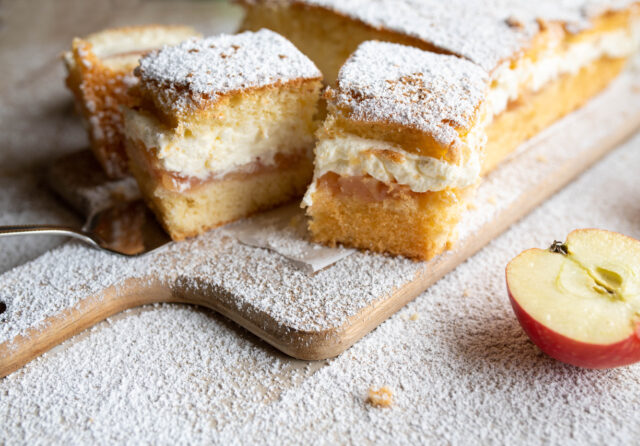 Cake with junkie apple sauce and whipped cream on wooden cutting board