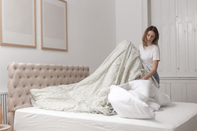 Woman changing bed linens at home in her bedroom, cozy domestic lifestyle, housewife cleaning, tidying up bedroom, housework concept.