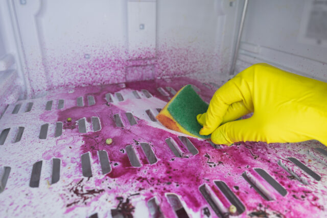 A cleaning lady in rubber gloves washes the freezer. Cleaning the refrigerator. Selective focus. Copy space.