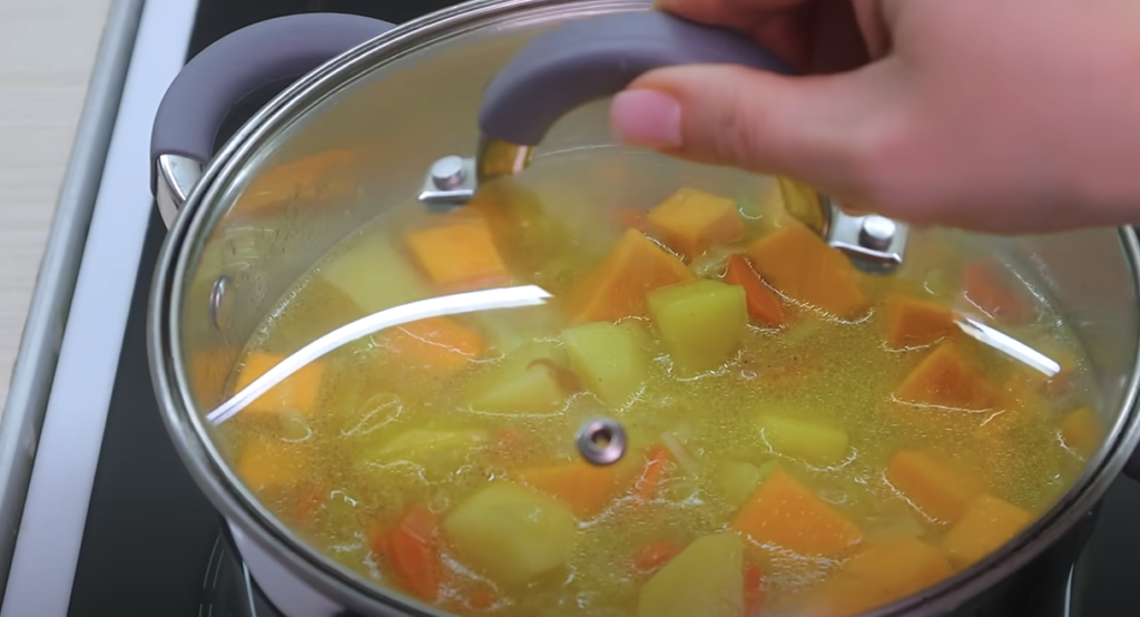 Lahodná krémová dýňová polévka se zeleninou a bramborami podávaná s opečeným voňavým chlebem - teplá a sytá večeře na stole!