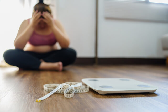 Obese Woman with fat upset bored of dieting Weight loss fail Fat diet and scale sad asian woman on weight scale at home weight control