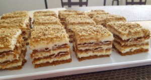 Nepečené řezy z Lotus sušenek s mascarpone: Karamelové potěšení bez pečení Vrstvené nepečené řezy ze sušenek Lotus Biscoff s krémem z mascarpone, posypané drcenými sušenkami a ořechy na servírovacím talíři.
