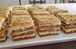 Nepečené řezy z Lotus sušenek s mascarpone: Karamelové potěšení bez pečení Vrstvené nepečené řezy ze sušenek Lotus Biscoff s krémem z mascarpone, posypané drcenými sušenkami a ořechy na servírovacím talíři.