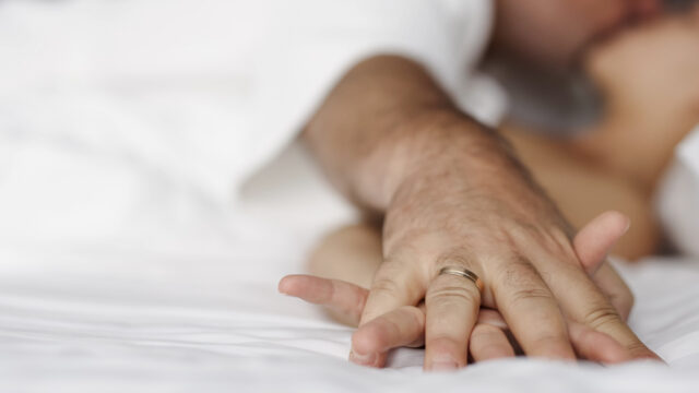 A close-up of a couple's hands intertwined on the bed, capturing a moment of relaxation and intimacy.