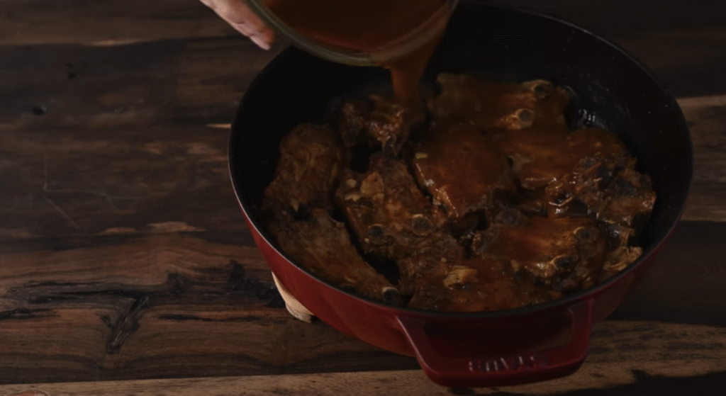 Gurmánská vepřová žebírka v česnekovo-rajčatové omáčce s houbami, slaninou a křupavou bagetkou