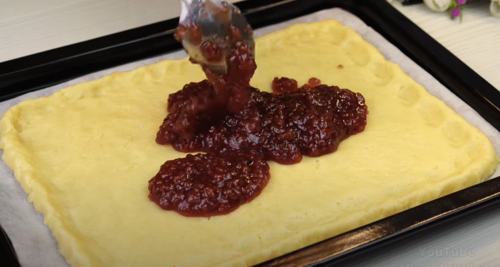 Lahodný drobenkový koláč ze zakysané smetany s oblíbeným džemem – tradiční sladká pochoutka plná křupavé drobenky