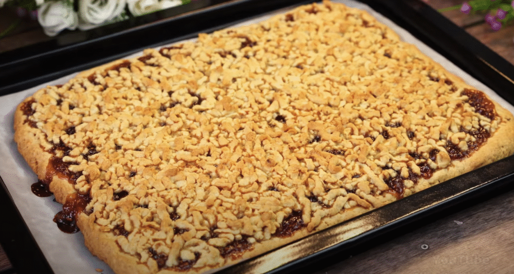 Lahodný drobenkový koláč ze zakysané smetany s oblíbeným džemem – tradiční sladká pochoutka plná křupavé drobenky