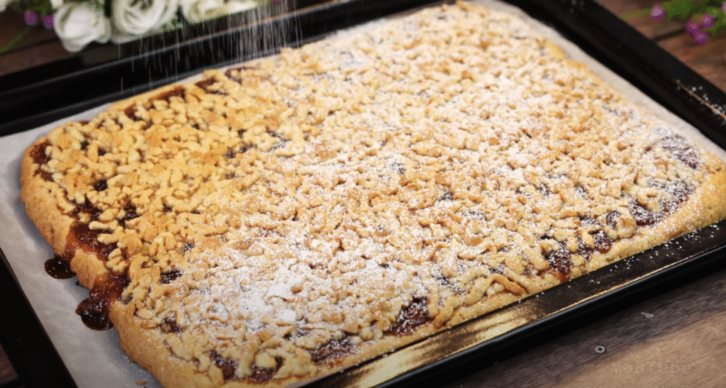 Lahodný drobenkový koláč ze zakysané smetany s oblíbeným džemem – tradiční sladká pochoutka plná křupavé drobenky