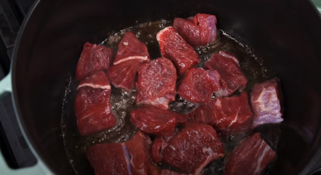 Pomalu dušené hovězí na červeném víně s kořenovou zeleninou a žampiony, podávané s jemnou bramborovou kaší