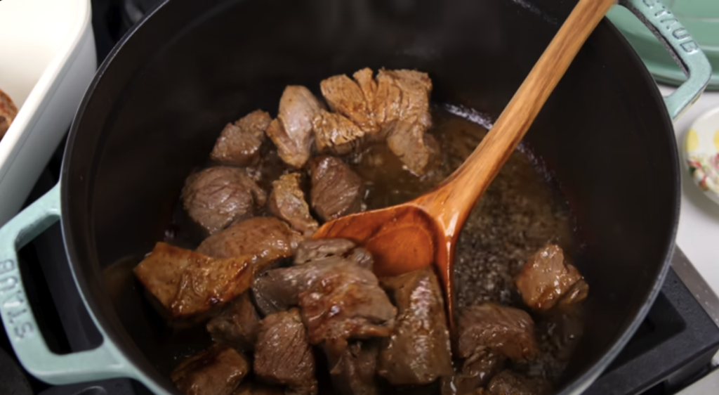 Pomalu dušené hovězí na červeném víně s kořenovou zeleninou a žampiony, podávané s jemnou bramborovou kaší