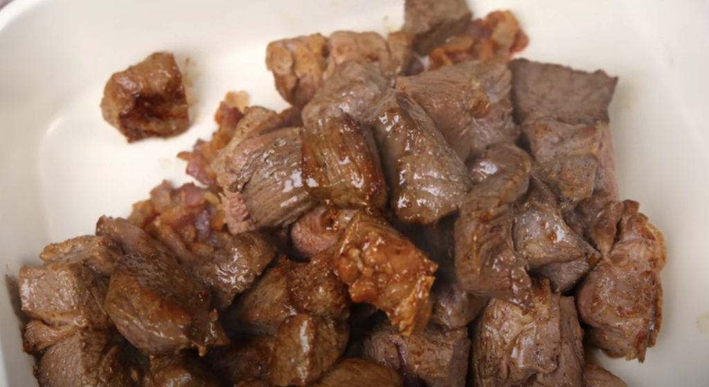 Pomalu dušené hovězí na červeném víně s kořenovou zeleninou a žampiony, podávané s jemnou bramborovou kaší