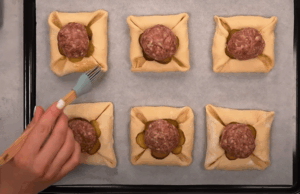Výborný recept na masové kuličky obalené v listovém těstu, sypané sýrem!