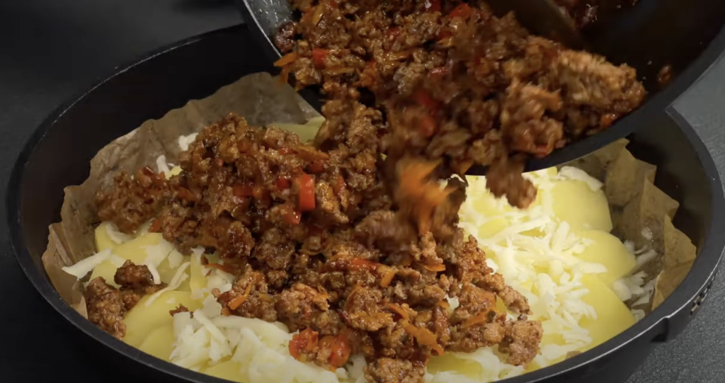 Slaný bramborový koláč ve tvaru pizzy s mletým masem, zeleninou a mozzarellou