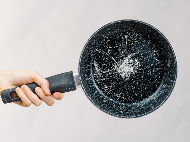 Hand holding scratched frying pan