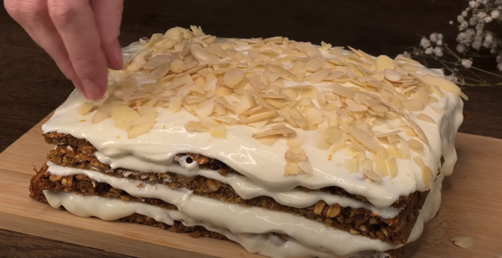 Vrstvený mrkvový dort s datlemi, vločkami, pomerančovým krémem a mandlemi