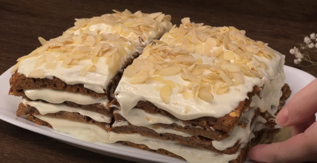 Vrstvený mrkvový dort s datlemi, vločkami, pomerančovým krémem a mandlemi