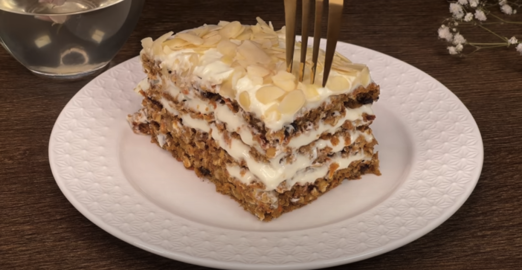 Vrstvený mrkvový dort s datlemi, vločkami, pomerančovým krémem a mandlemi