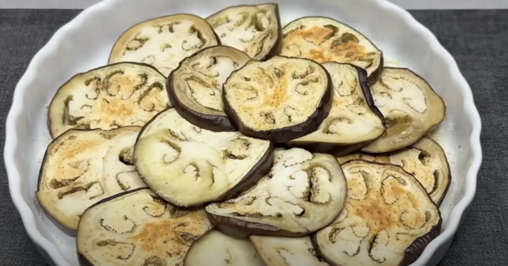 Gratinované vrstvené lilky s cibulovo-klobásovou směsí a sýrem