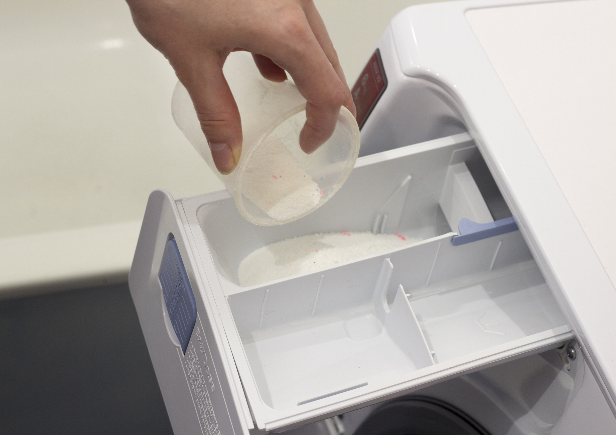 Sypání pracího prášku do pračky.