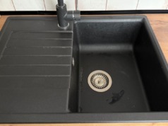 Smrdí vám odpad v dřezu? Domácí směs ze sody a octa zápach odstraní za 15 minut Černý kuchyňský dřez s vodovodní baterií.
