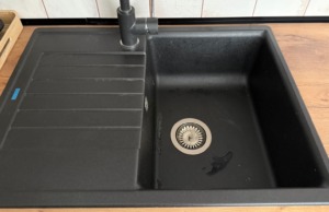 Smrdí vám odpad v dřezu? Domácí směs ze sody a octa zápach odstraní za 15 minut Černý kuchyňský dřez s vodovodní baterií.