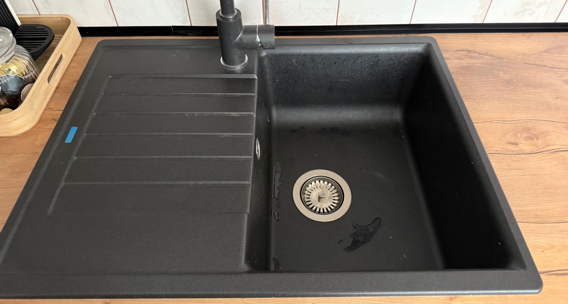 Černý kuchyňský dřez s vodovodní baterií.