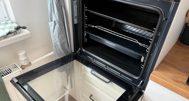 Otevřená kuchyňská trouba s vytaženými rošty.