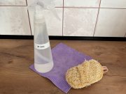 Rozprašovač s čisticím prostředkem, přírodní houbička a utěrka na kuchyňské lince.