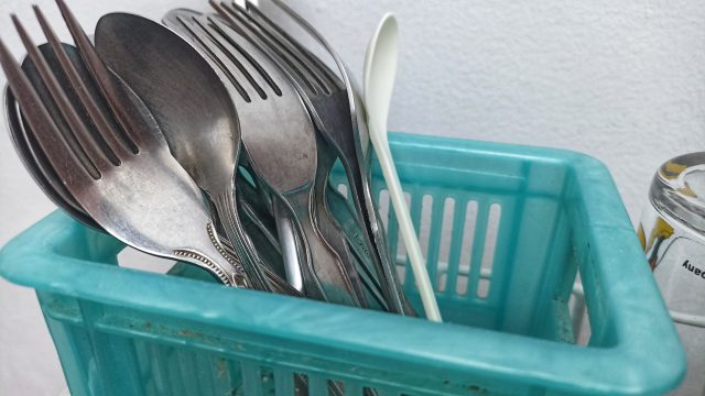 group of stainless steel spoons dan forks stored in a blue container.