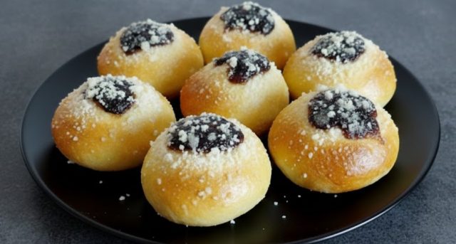 Domácí měkoučké koláčky s povidly, tvarohem a drobenkou na černém talíři.