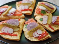 Smaženky na chleba Smažené vaječné omelety na černém talíři obložené čerstvou zeleninou, ředkvičkami, cibulí a kyselou okurkou