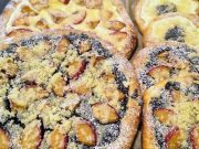 Poctivé kynuté koláče s tvarohem, mákem a slívami Dva velké a několik menších čerstvě upečených kynutých koláčů na pečicím papíře. Zdobené jsou makovou a tvarohovou náplní, plátky slív a bohatě posypané máslovou drobenkou a moučkovým cukrem.