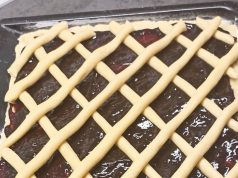 Tradiční mřížkový koláč s povidly: Bleskové křehké těsto z robotu Čerstvě upečený křehký koláč na plechu s bohatou vrstvou tmavých švestkových povidel, který je na povrchu ozdobený pravidelnou mřížkou ze zlatavě upečeného těsta.