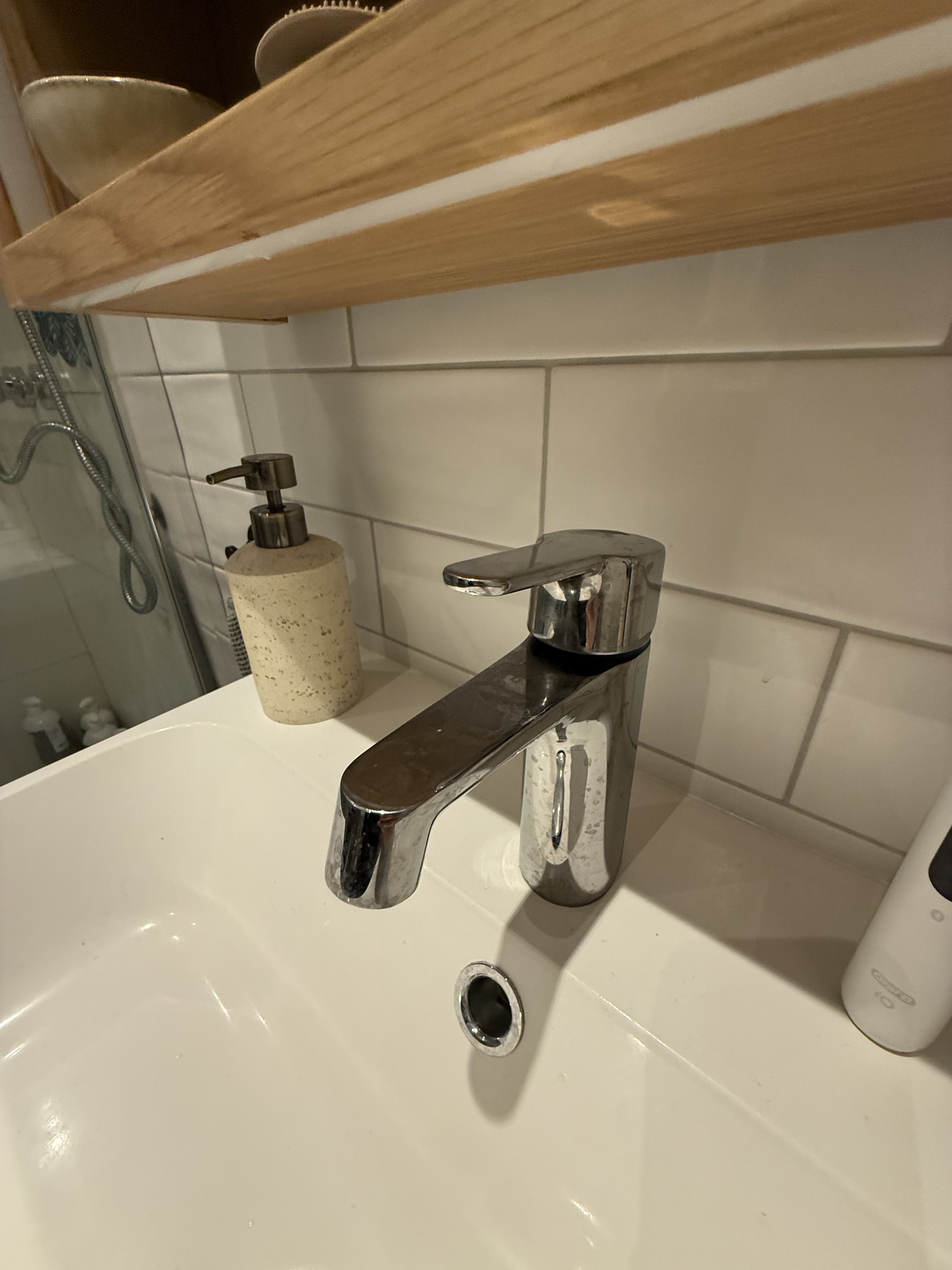 Detail znečištěné chromové vodovodní baterie s kapkami vody před vyčištěním.