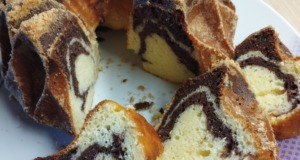 Vláčná tvarohová bábovka s kakaovým mramorováním: Recept na nejjemnější dezert Domácí mramorová bábovka s tvarohem na bílém talíři, nakrájená na plátky, s viditelnou jemnou strukturou a kakaovým vzorem na dřevěném stole.