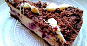 Čokoládový drobenkový koláč s mascarpone a borůvkami: Luxusní dezert bez námahy Kousek čokoládového drobenkového koláče s krémovou vrstvou a polevou.“