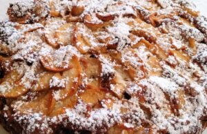 Neskutečně dobrý „překlopený“ koláč s jablky, rumovým krémem a posypkou Domácí jablečný koláč posypaný moučkovým cukrem s plátky jablek.