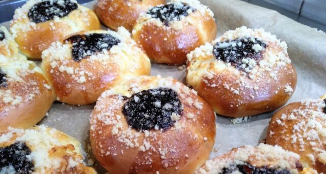 Kynuté koláče s tvarohem, drobenkou a ovocnou náplní na plechu.