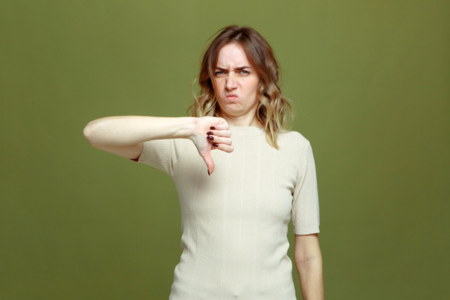 Displeased young woman show thumb down dislike gesture disappointed with service, feel dissatisfied, disgust