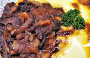 Pomalu pečená krkovička v pikantní marinádě: Maso, které se rozplývá Pečená vepřová krkovička s houbami a šťávou, podávaná s bramborovou kaší.