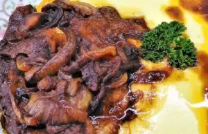 Pomalu pečená krkovička v pikantní marinádě: Maso, které se rozplývá Pečená vepřová krkovička s houbami a šťávou, podávaná s bramborovou kaší.