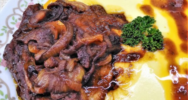 Pečená vepřová krkovička s houbami a šťávou, podávaná s bramborovou kaší.