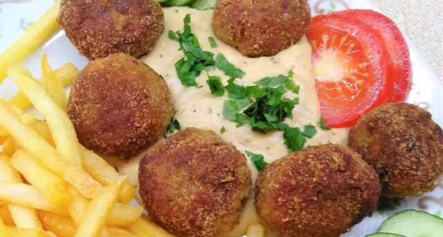 Smažené masové kuličky s omáčkou, hranolkami a zeleninovou oblohou.