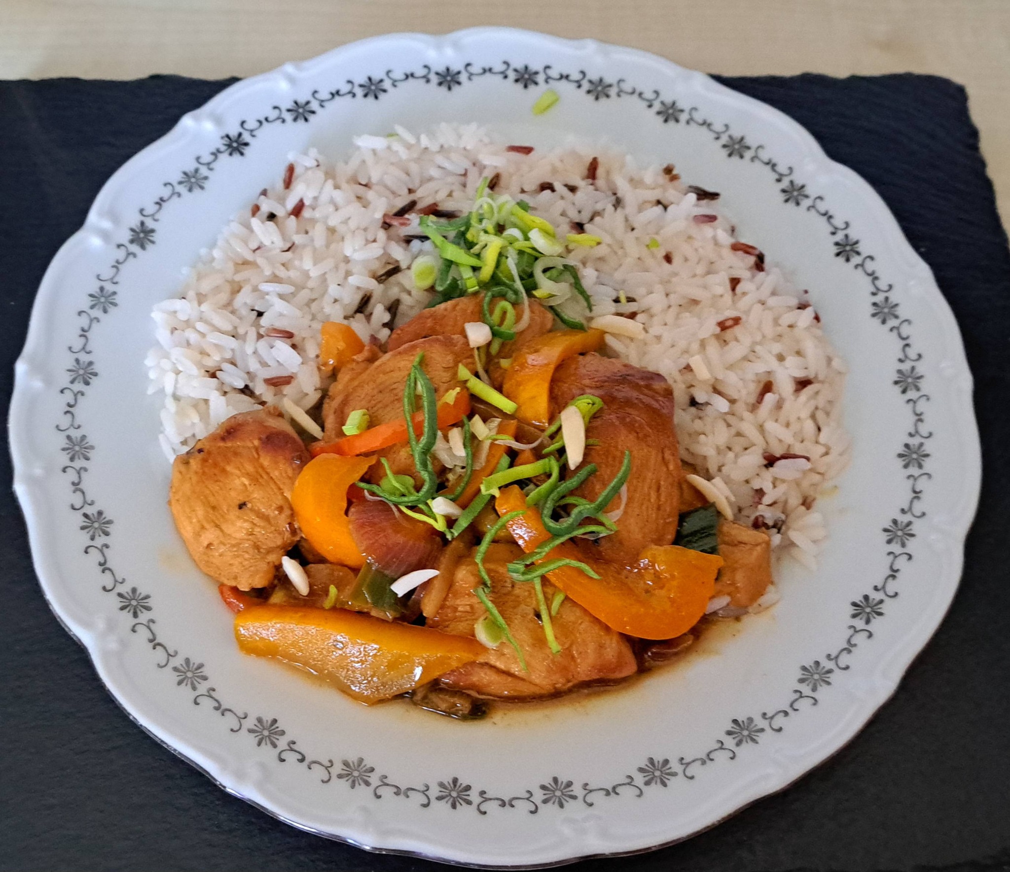 Talíř s barevnými kuřecími fajitas (papriky, pórek, cibule a maso) podávaná s bílou rýží a čerstvým citronem.