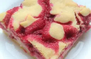Křehký malinový koláč s pudinkem a tvarohem: Neodolatelný dezert s vůní mandlí Malinový koláč s tvarohovou vrstvou a světlým těstem na povrchu.