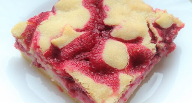 Malinový koláč s tvarohovou vrstvou a světlým těstem na povrchu.
