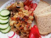 Pomalu pečená krkovice na cibuli a slanině: Poctivá dobrota z jednoho pekáče Pečená krkovice se zeleninovou směsí, chlebem a čerstvou oblohou.